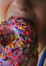 A kid enjoying a donut with sprinkles