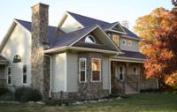 A pretty house with stone exteriors and a metal roof.